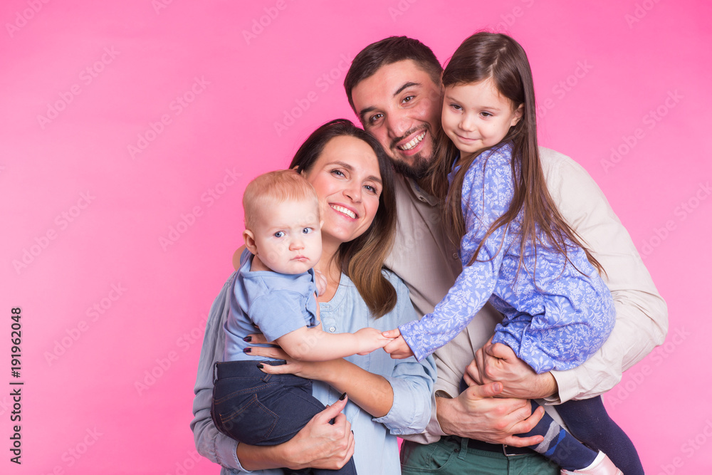 Cute family posing and smiling at camera together on pink background Cute family posing and smiling at camera together on pink background