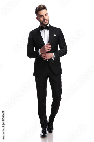 young sexy man in tuxedo and bowtie fixing his sleeve photo