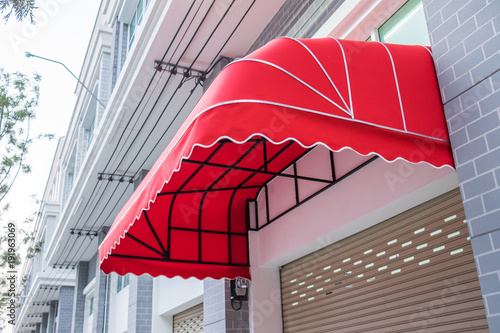 Red awning mounted on the front door of the shop. photo