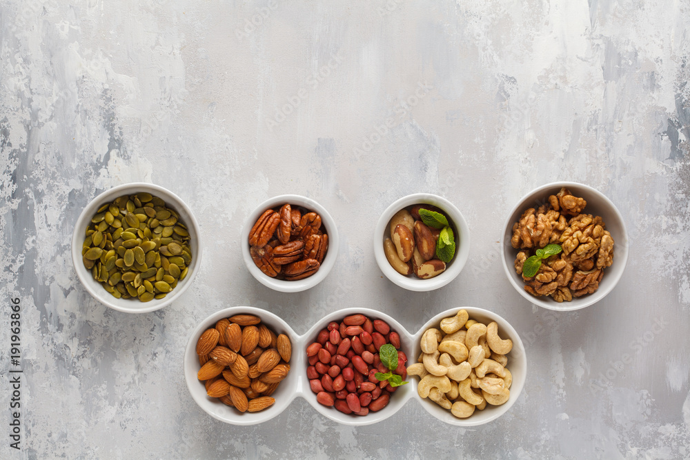 A variety of nuts and seeds in a white bowls, top view, copy space, food background. Healthy vegetarian food concept. A variety of nuts and seeds in a white bowls, top view, copy space, food background. Healthy vegetarian food concept.