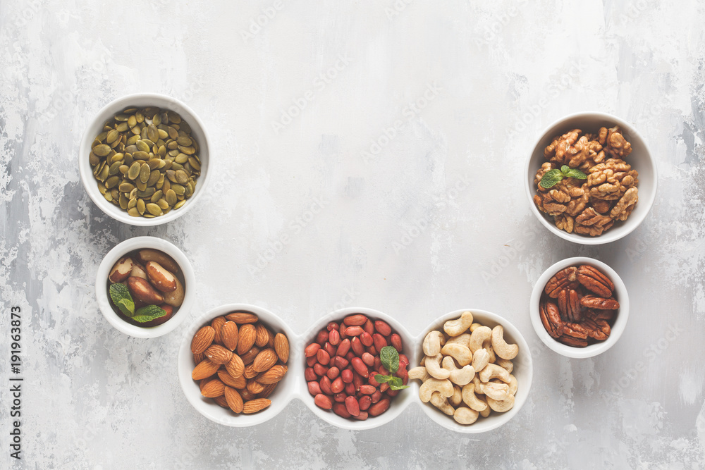 A variety of nuts and seeds in a white bowls, top view, copy space, food background. Healthy vegetarian food concept. A variety of nuts and seeds in a white bowls, top view, copy space, food background. Healthy vegetarian food concept.