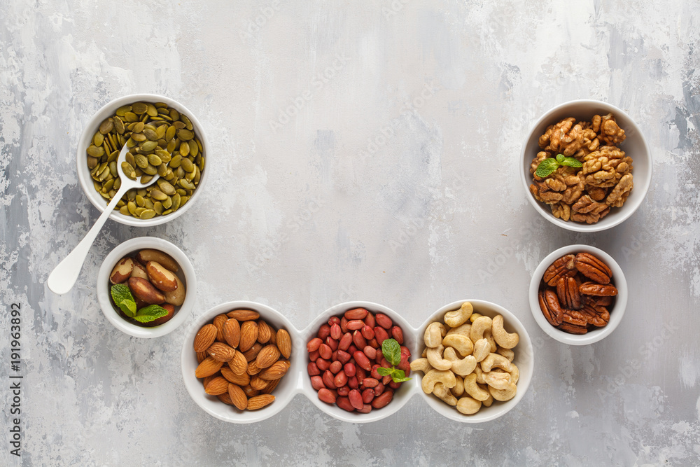 A variety of nuts and seeds in a white bowls, top view, copy space, food background. Healthy vegetarian food concept. A variety of nuts and seeds in a white bowls, top view, copy space, food background. Healthy vegetarian food concept.