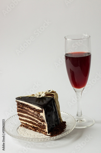 piece of chocolate cake on a glass saucer glass of red wine