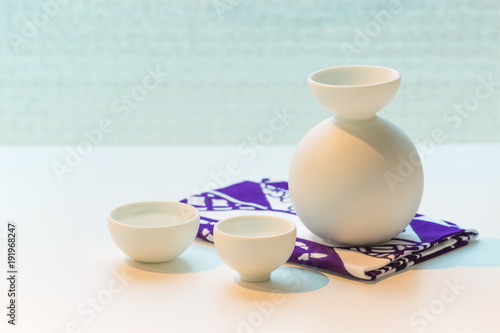 Set for Japanese sake on a napkin with a Japanese pattern on a white table.
