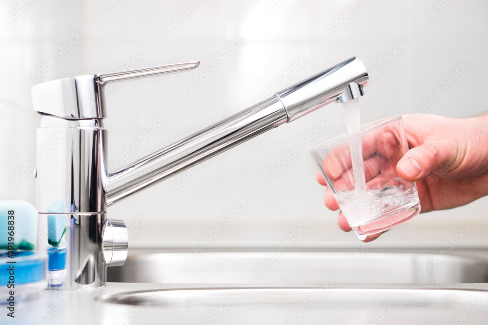 Filling glass with tap water. Modern faucet and sink in home kitchen