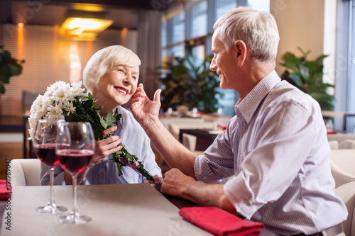 Forever love. Sweet cheerful mature couple having date while smiling and man touching woman face