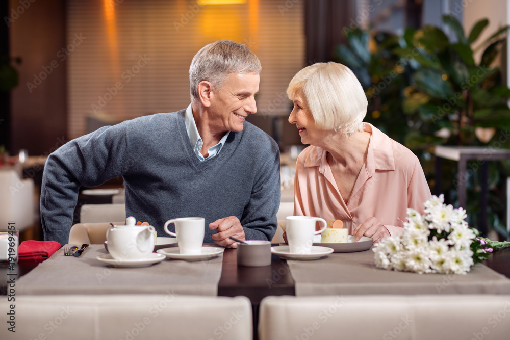 Sweet life. Good looking positive mature couple posing in profile while smiling and having desert Sweet life. Good looking positive mature couple posing in profile while smiling and having desert