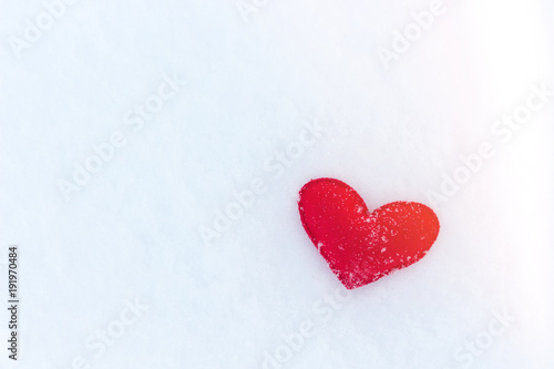 red felt heart figure on snow  winter day with sun glare