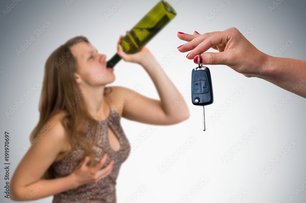 Woman drinking alcohol and her friend showing car keys Woman drinking alcohol and her friend showing car keys