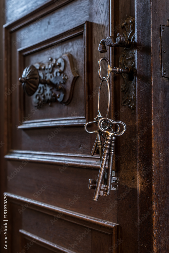 Obraz premium Old Keys in a Keyhole. Old rusty wooden door with keys.