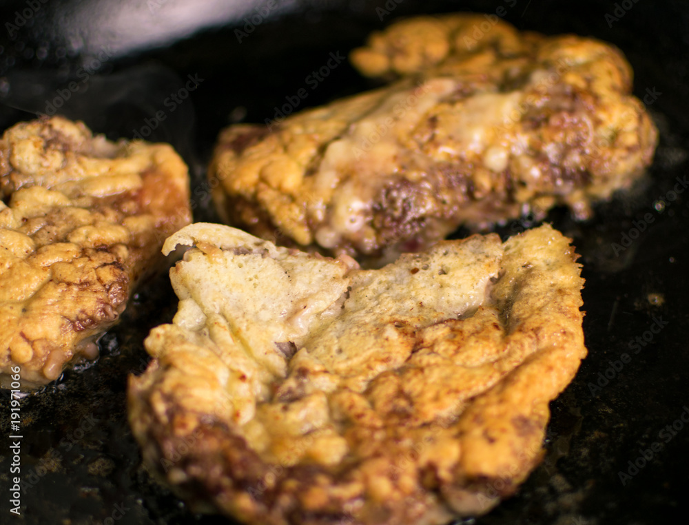 Pork chop boneless in batter is fried in a frying pan. Pork chop boneless in batter is fried in a frying pan.