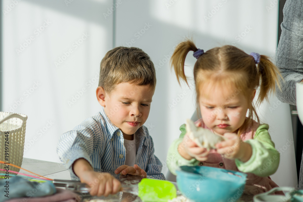 Two children are cooking something from the dough. Two children are cooking something from the dough.