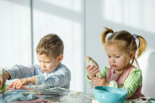 Two children are cooking something from the dough. photo