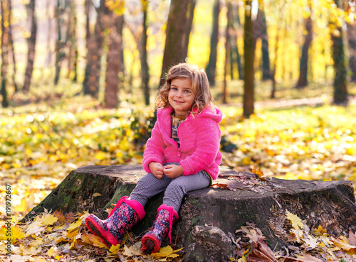 Portrait of little girl sitting in autumn park.