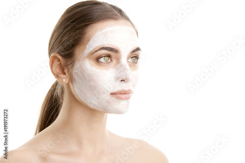 Young woman with beauty mask on her face. Close-up studio shot of young woman wearing a face mask against at isolated background with copy space.