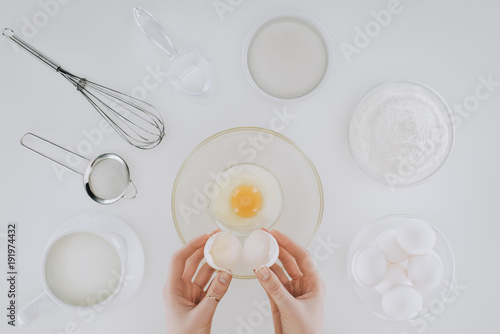 cropped shot of person holding eggshell while cooking pancakes isolated on grey