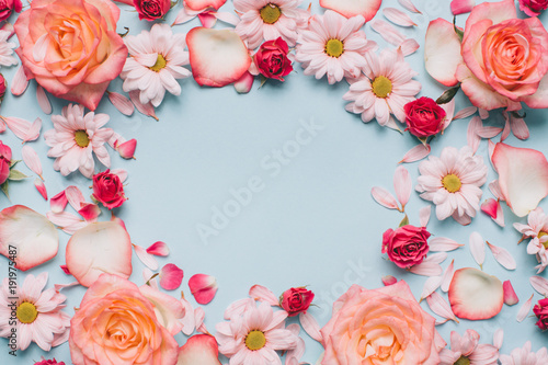 Floral pattern of roses buds, camomiles and petals on blue background. Flat lay, Top view.