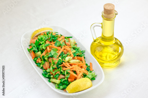 A plate of fresh vegetable salad and a carafe of olive oil.