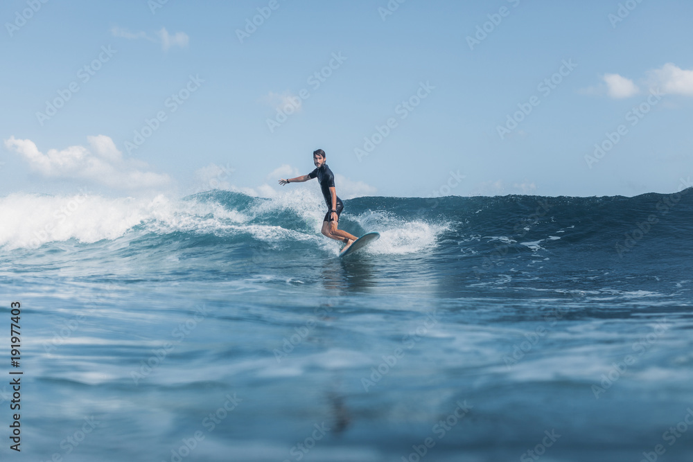 sportsman surfing wave on board in ocean