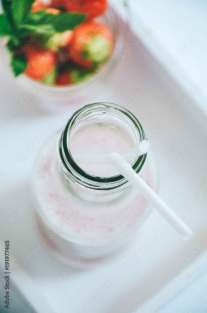 Strawberry milkshake in glass bottle with drinking straw garnished with fresh strawberries on white background Strawberry milkshake in glass bottle with drinking straw garnished with fresh strawberries on white background