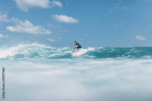 active man riding wave on surf board in ocean