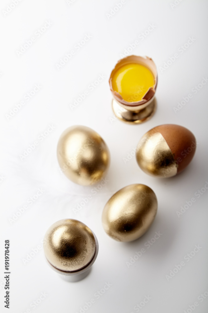 Eggs painted golden with yolk in egg stand on white background. Easter concept, copy space Eggs painted golden with yolk in egg stand on white background. Easter concept, copy space