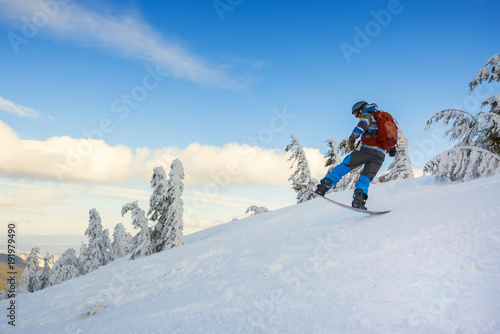Snowboarder jumps on the background of blue sky