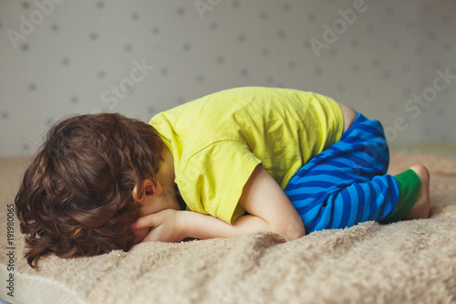 Fototapet Tired toddler boy lying on the bed with his face down