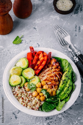 Vegetable bowl lunch with grilled chicken and quinoa, spinach, avocado, brussels sprouts, paprika and chickpea