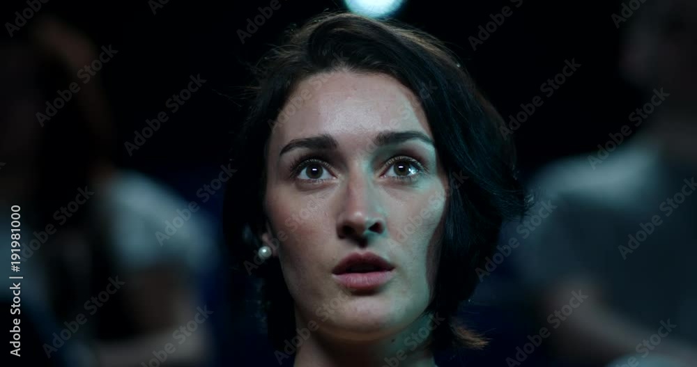 A woman reacts impressed to a moment in a film while at the cinema A woman reacts impressed to a moment in a film while at the cinema