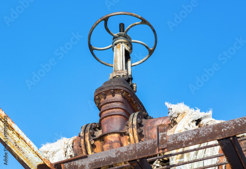 Old rusty pipeline with valve against the blue sky background