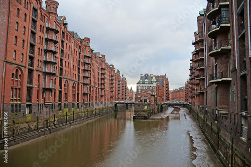 Speicherstadt. Port warehouse in Hamburg. Hamburg is a harsh German city. The urban landscape of northern Germany. View of city canals from the bridge. © romanklevets