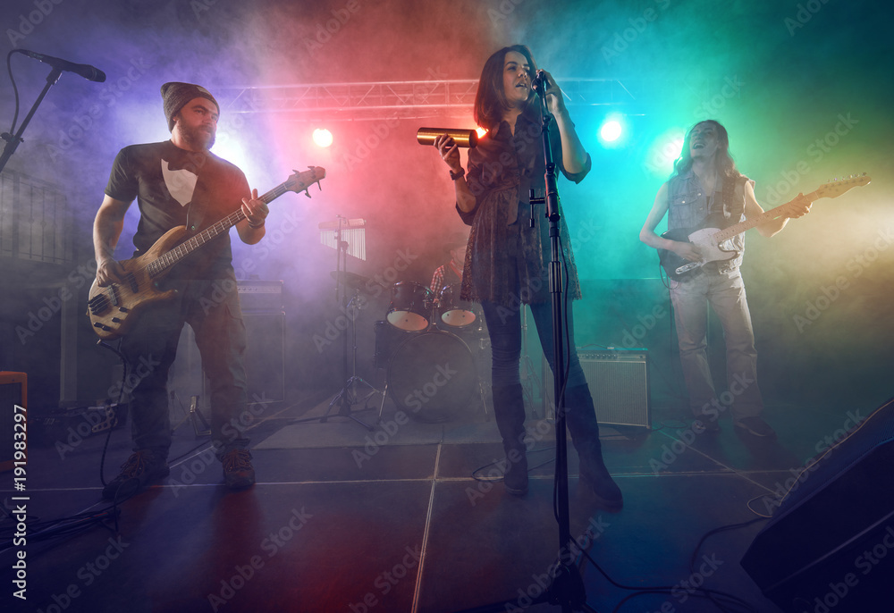Fototapeta premium Rock band performs on stage. Guitarist, bass guitar and drums.