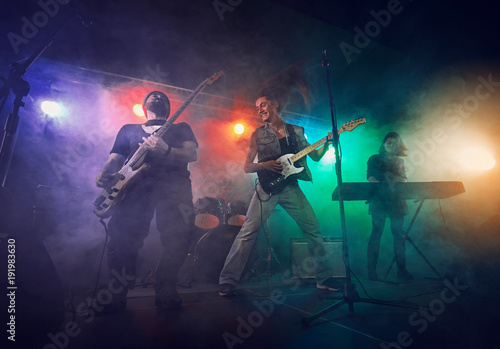 Rock band performs on stage. Guitarist, bass guitar and drums. © Voloshyn Roman