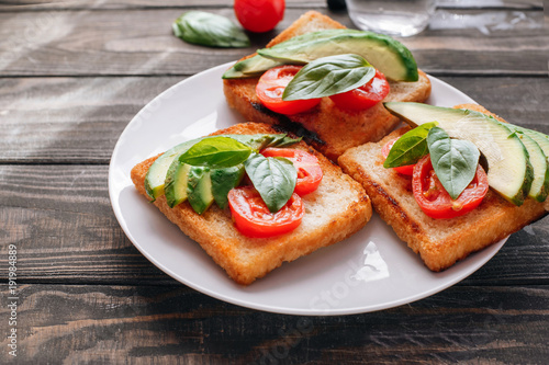 Dietary healthy food. Bread with avacado  tomatoes and Basil