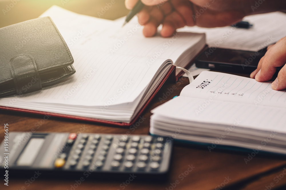 Businessman hand holds pen working on calculator and notepads to calculate budget, business financial concept Businessman hand holds pen working on calculator and notepads to calculate budget, business financial concept