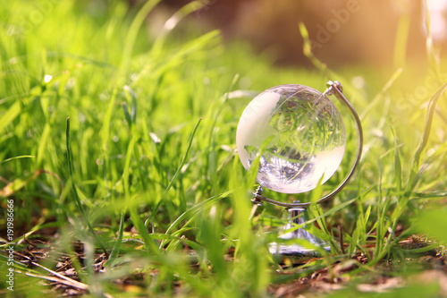 low angle small crystal globe in the grass. travel and global issues concept. photo