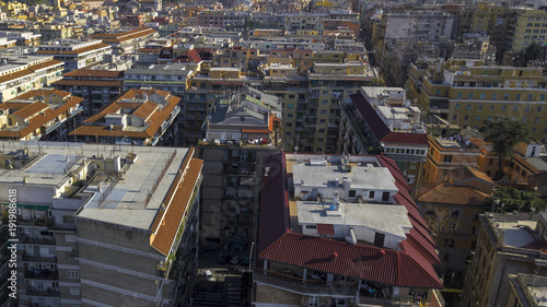 Aerial view of a group of buildings in the Tuscolana district in Rome, Italy. The roofs are passable and with antennas and TV. down the sunlit streets there are cars and trees. © Stefano Tammaro