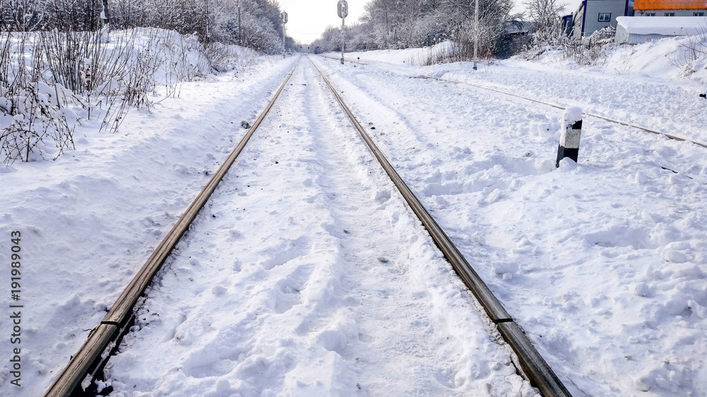 The path between the sleepers in with a bliss. Sleepers from the train, electric train in city in the winter. They are covered with snow from a storm. The road going into the distance.