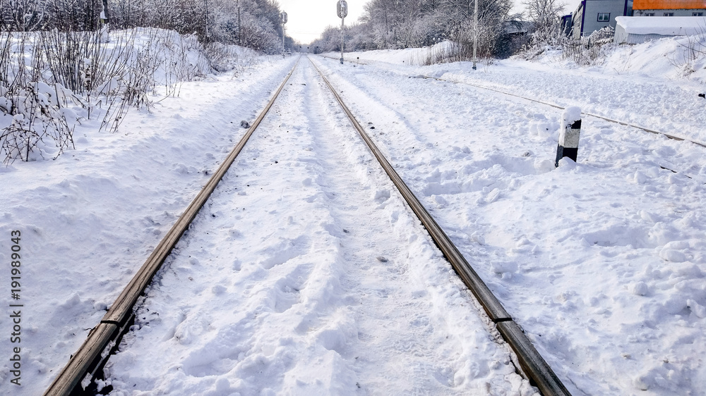 The path between the sleepers in with a bliss. Sleepers from the train, electric train in city in the winter. They are covered with snow from a storm. The road going into the distance. The path between the sleepers in with a bliss. Sleepers from the train, electric train in city in the winter. They are covered with snow from a storm. The road going into the distance.