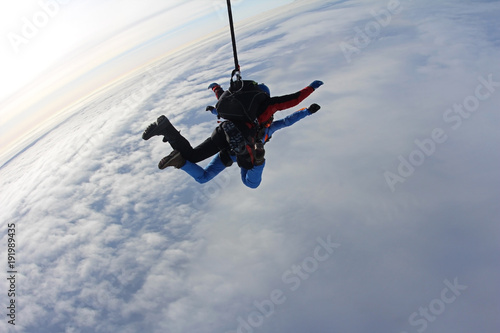 Skydiving. Tandem is flying above white clouds.