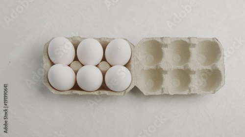 woman's hand open an eggbox with white eggs ant take off oneof them photo