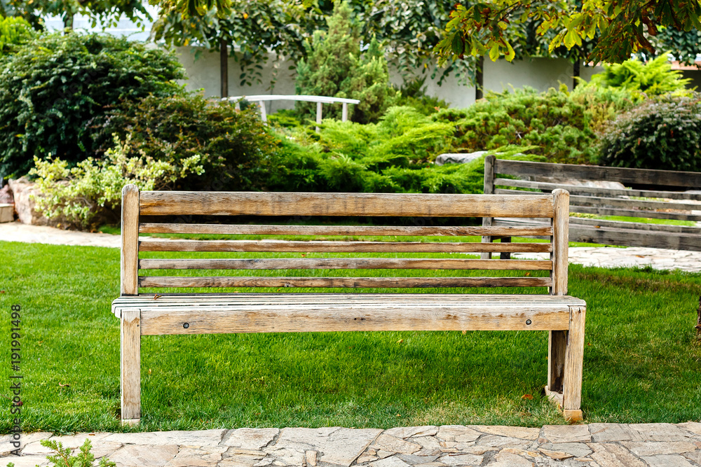 Wooden empty bench in a city park. Good place to relax on summer day.