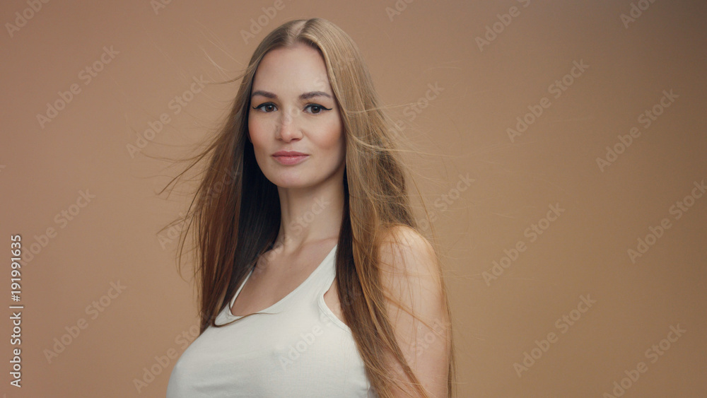 beauty woman model in studio on beige background with wind in hair bllowing it. white top beauty woman model in studio on beige background with wind in hair bllowing it. white top
