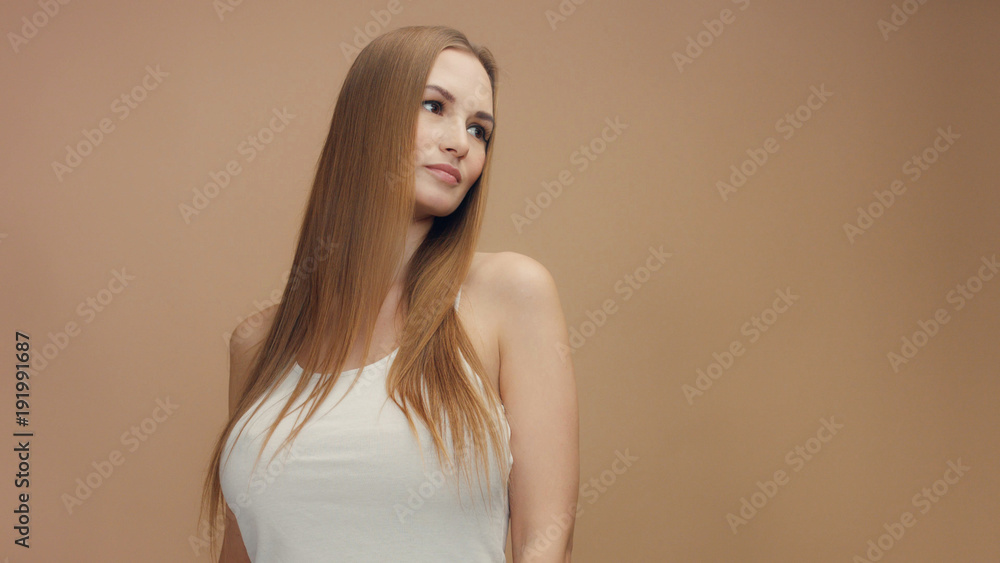 beauty woman model in studio on beige background with wind in hair bllowing it. white top beauty woman model in studio on beige background with wind in hair bllowing it. white top