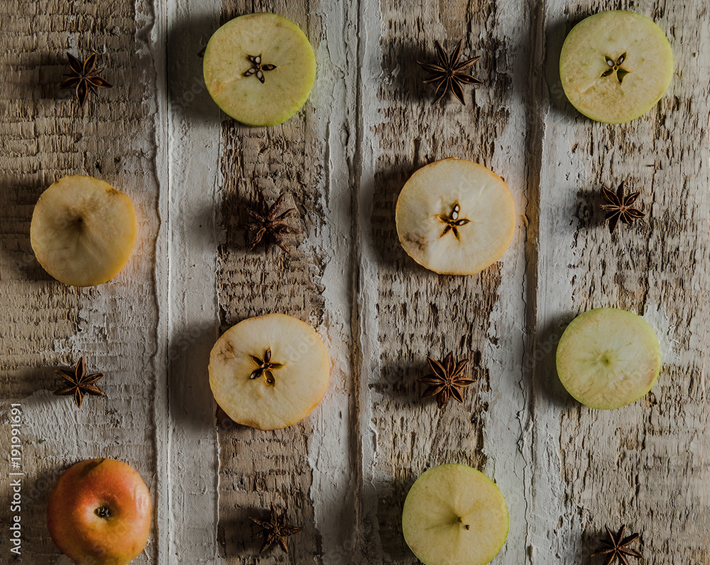 apples cut in circles with star anise on a rough wooden surface, toned creative background apples cut in circles with star anise on a rough wooden surface, toned creative background