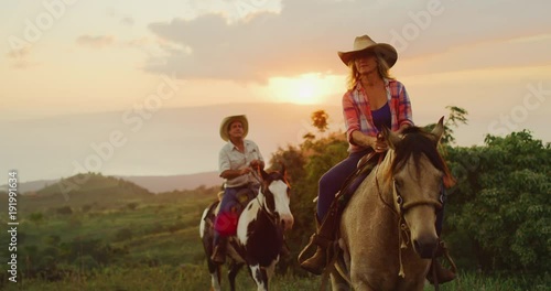 Couple horseback riding at sunset photo