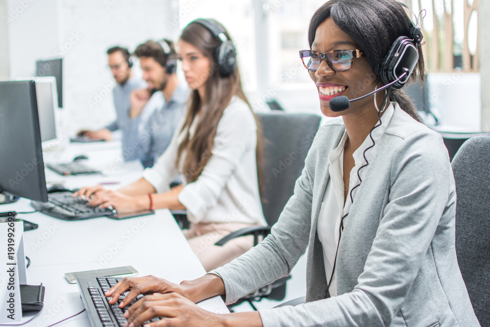 Smiling young woman with headset working in call center. Smiling young woman with headset working in call center.