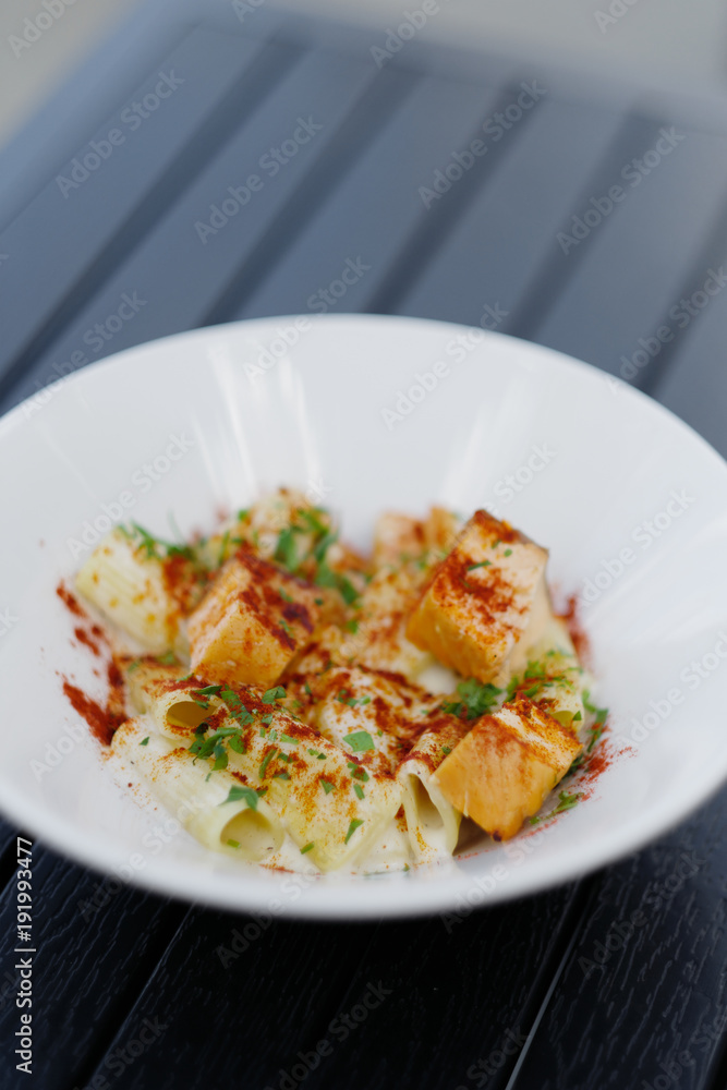 Pasta with pink salmon in a white plate on the table Pasta with pink salmon in a white plate on the table