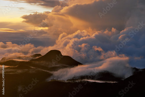 Orange dawn on the mountain. Mountain tops in the clouds